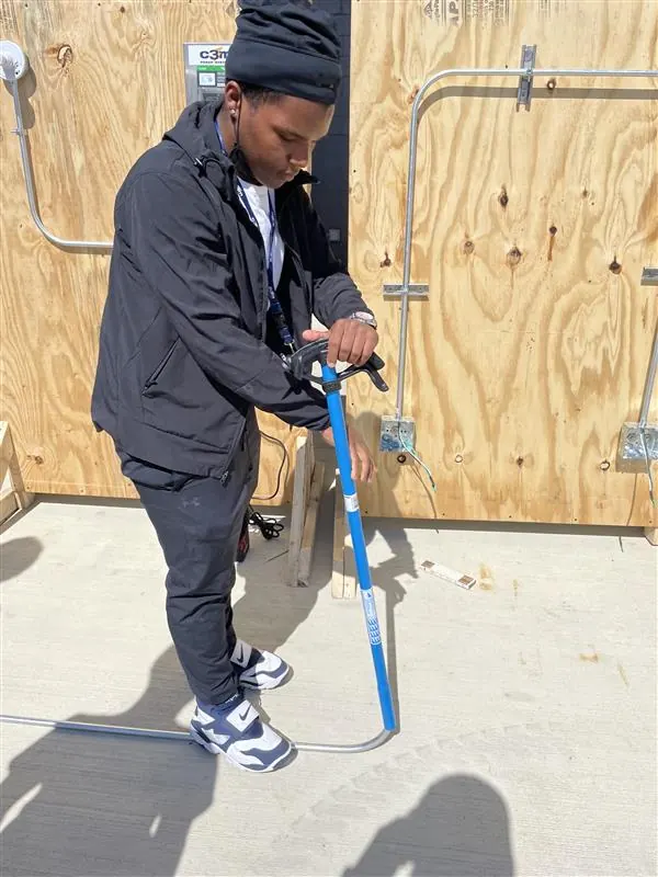 An apprentice marking out a layout against a plywood wall.