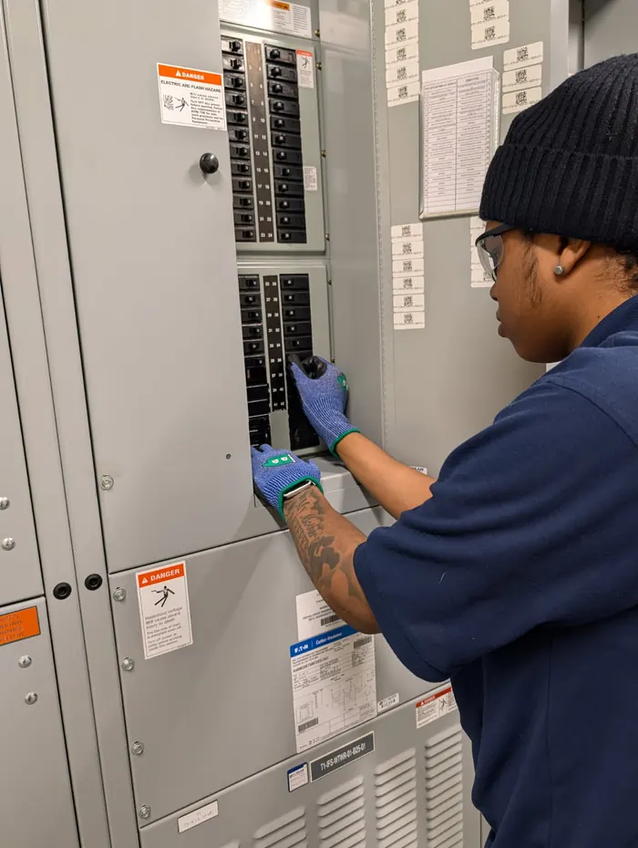 An apprentice working inside an electrical panel board.
